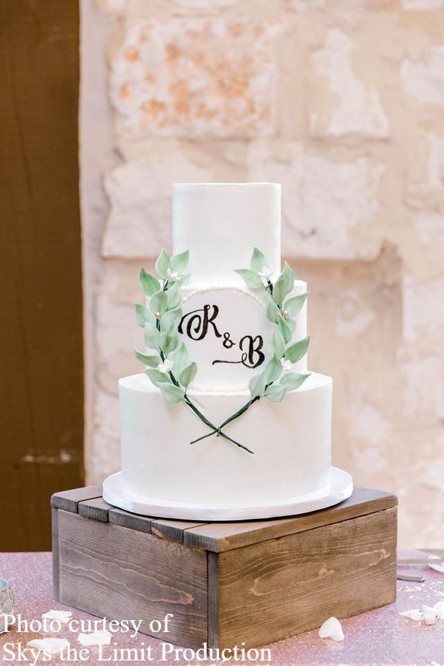 Wedding cake with greenery wreath and monogram by Sweet By Design